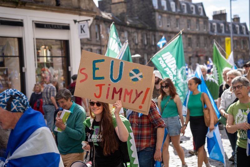 Green member holding placard