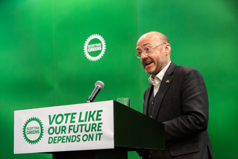 Patrick Harvie stands behind podium with sign reading vote like our future depends on it